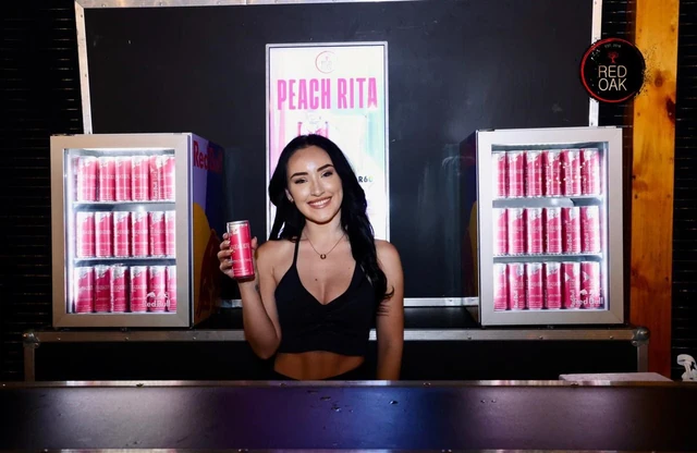 A Peach Rita promotion stand flanked by lit drinks fridges.