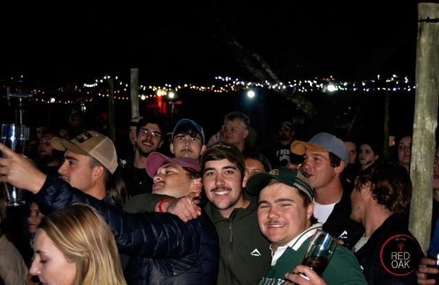 A night-time crowd outdoors with the town lights behind them.