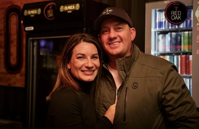 A couple together beside the Olmeca-branded bar fridges.