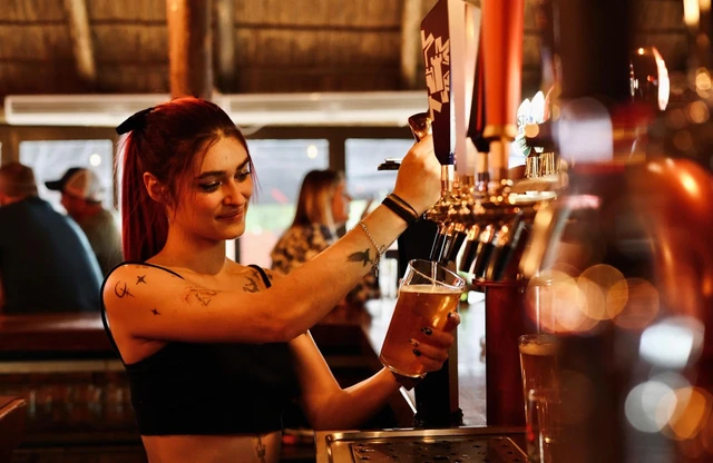 A bartender pouring a draught beer at the Red Oak taps.