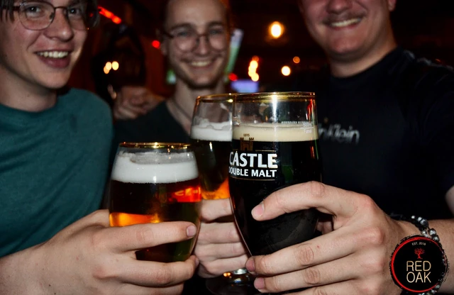 Three guests raising Castle draught glasses in a toast.