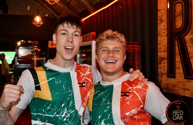 Two guests in South African supporters' shirts celebrating a match.