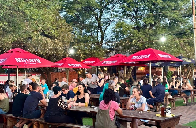The Red Oak beer garden by day, with red umbrellas and full tables.