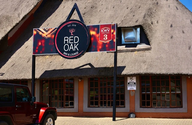 The Red Oak exterior with the round logo sign on the thatched building.