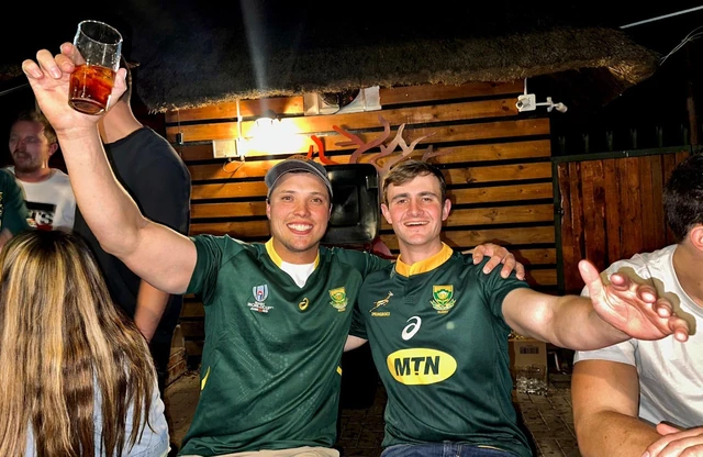 Two guests in Springbok shirts celebrating with a drink raised.