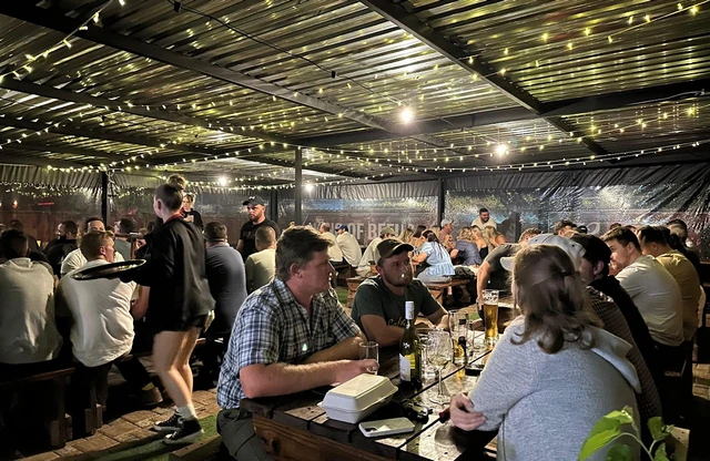 A busy covered patio under fairy lights, every table taken.
