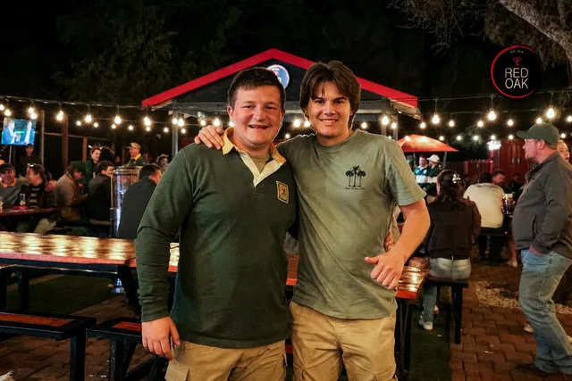 Two friends in green rugby shirts with arms around each other at the outdoor area.