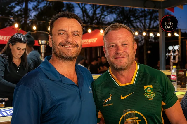 Two men posing together at dusk, one in a Springbok rugby jersey.