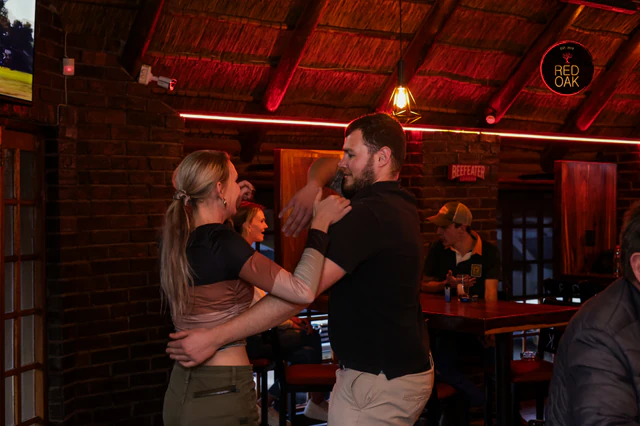A couple dancing together under the red lights inside Red Oak.