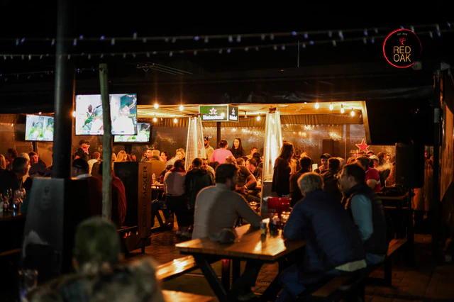 A packed night crowd watching rugby across the screens in Red Oak's covered outdoor area.